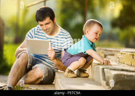 Padre e figlio giocando sulla tavoletta digitale esterno Foto Stock