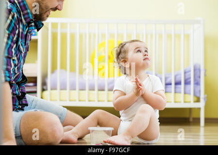 Padre Felice e la sua piccola figlia giocare con vari pulsanti a casa Foto Stock