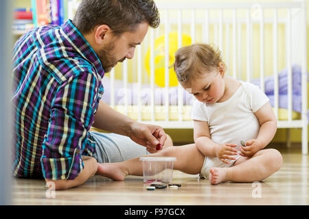 Padre Felice e la sua piccola figlia giocare con vari pulsanti a casa Foto Stock