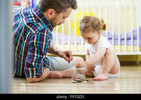 Padre Felice e la sua piccola figlia giocare con vari pulsanti a casa Foto Stock