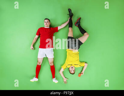 Arbitro dando cartellino rosso ad un giocatore di calcio. Studio shot su sfondo verde. Foto Stock