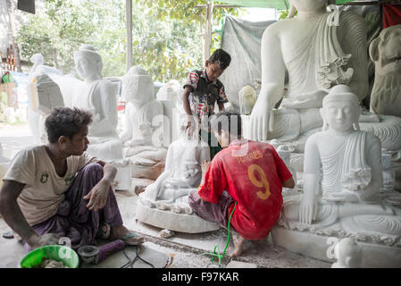 MANDALAY, Myanmar - gli artigiani locali intraprendono il lavoro polveroso e sfrenato di intagliare statue del Buddha in marmo. Poiché il buddismo è la religione dominante in Myanmar, c'è una notevole domanda di statue, con i clienti in grado di scegliere tra una miriade di pose, dimensioni e stili. Gli artigiani sono raggruppati in una strada nel quartiere Chanmyathazi di Mandalay vicino alla Pagoda Mahamuni. Foto Stock