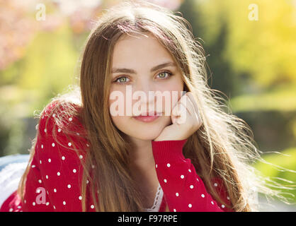 Ritratto di bella ragazza in rosso cardigan in green prak Foto Stock