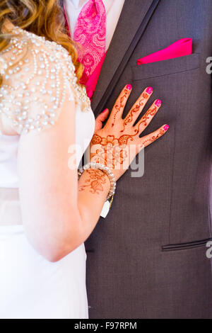Tatuaggi di nozze di henna su un Indiano si sposa a una chiesa cattolica accanto al suo sposo dopo la loro cerimonia nuziale. Foto Stock