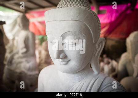 MANDALAY, Myanmar - gli artigiani locali intraprendono il lavoro polveroso e sfrenato di intagliare statue del Buddha in marmo. Poiché il buddismo è la religione dominante in Myanmar, c'è una notevole domanda di statue, con i clienti in grado di scegliere tra una miriade di pose, dimensioni e stili. Gli artigiani sono raggruppati in una strada nel quartiere Chanmyathazi di Mandalay vicino alla Pagoda Mahamuni. Foto Stock