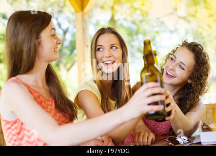 Tre amici felici di bere birra, chattare e divertirsi in pub garden Foto Stock