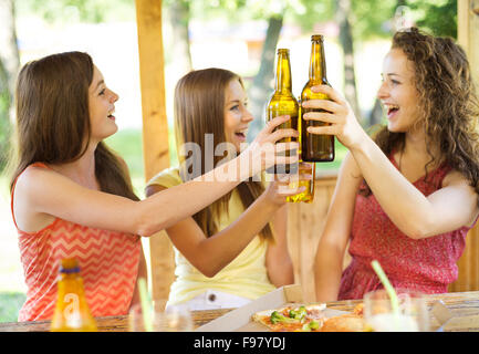 Tre amici felici di bere birra, chattare e divertirsi in pub garden Foto Stock
