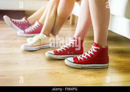 Tre giovani ragazze seduti sul divano, closup sulle gambe e sneakers Foto Stock