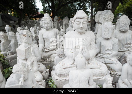 MANDALAY, Myanmar - gli artigiani locali intraprendono il lavoro polveroso e sfrenato di intagliare statue del Buddha in marmo. Poiché il buddismo è la religione dominante in Myanmar, c'è una notevole domanda di statue, con i clienti in grado di scegliere tra una miriade di pose, dimensioni e stili. Gli artigiani sono raggruppati in una strada nel quartiere Chanmyathazi di Mandalay vicino alla Pagoda Mahamuni. Foto Stock