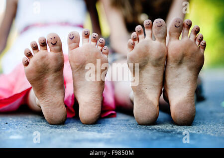 Funny piedi di due ragazze seduta su un marciapiede in parco verde Foto Stock