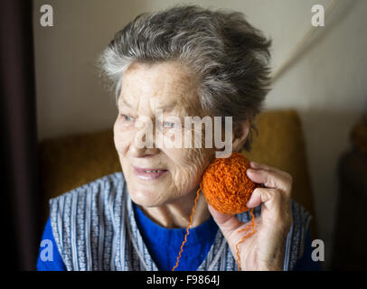 Ritratto di donna senior seduto in poltrona e maglia a casa Foto Stock