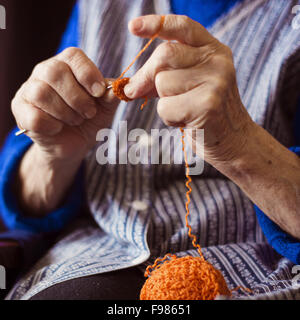 Le mani della donna senior con la maglia di lana e aghi di tessitura Foto Stock