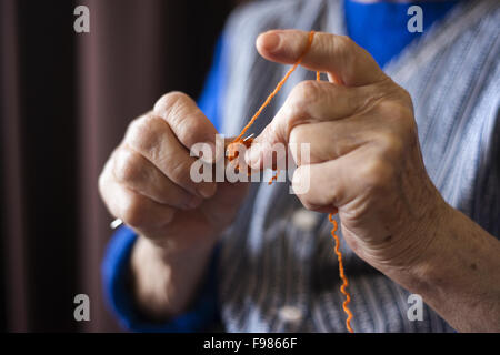 Le mani della donna senior con la maglia di lana e aghi di tessitura Foto Stock