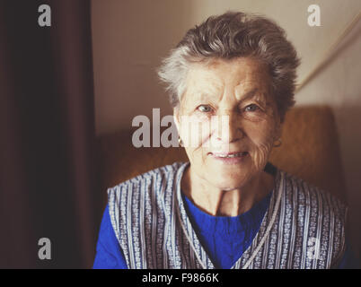 Ritratto di donna senior seduto in poltrona a casa Foto Stock