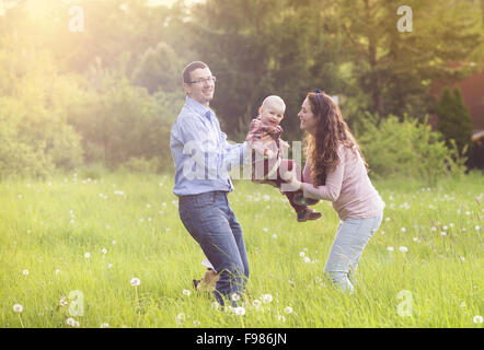 La famiglia felice giocando con il figlio sul prato Foto Stock