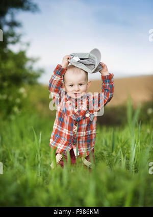 Carino piccolo ragazzo giocando nel verde della natura Foto Stock