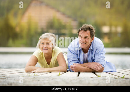 Coppia senior sdraiato e divertirsi sul molo Foto Stock