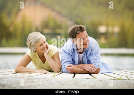 Coppia senior sdraiato e divertirsi sul molo Foto Stock