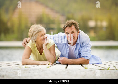 Coppia senior sdraiato e divertirsi sul molo Foto Stock