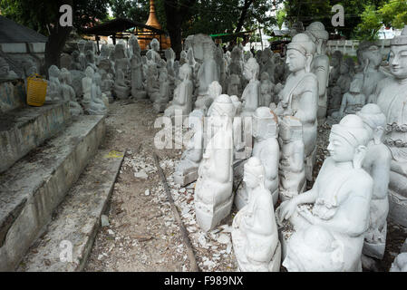 MANDALAY, Myanmar - gli artigiani locali intraprendono il lavoro polveroso e sfrenato di intagliare statue del Buddha in marmo. Poiché il buddismo è la religione dominante in Myanmar, c'è una notevole domanda di statue, con i clienti in grado di scegliere tra una miriade di pose, dimensioni e stili. Gli artigiani sono raggruppati in una strada nel quartiere Chanmyathazi di Mandalay vicino alla Pagoda Mahamuni. Foto Stock