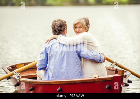 Coppia senior paddling in barca sulla montagna tarn Foto Stock