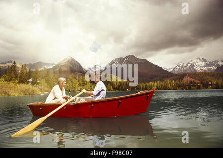 Coppia senior paddling in barca sulla montagna tarn Foto Stock