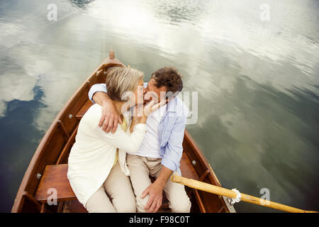 Coppia senior baciare sulla barca sulla montagna tarn Foto Stock