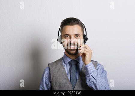 Operatore di call center isolato su bianco. Giovane bello hipster Uomo con cuffie. Foto Stock