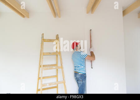 Giovane uomo misura della parete della nuova casa con livello Foto Stock