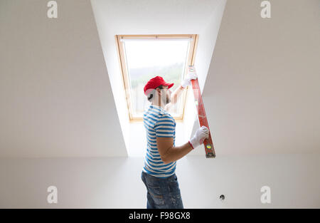 Giovane uomo misura della parete della nuova casa con livello Foto Stock