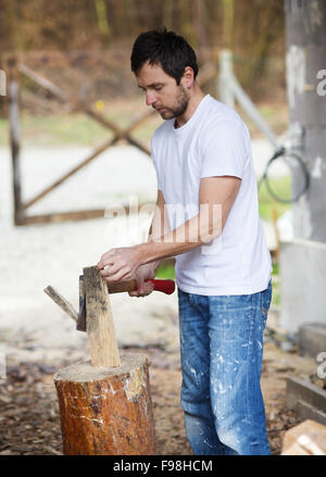 Giovane uomo trinciatura di legno nel suo cortile Foto Stock