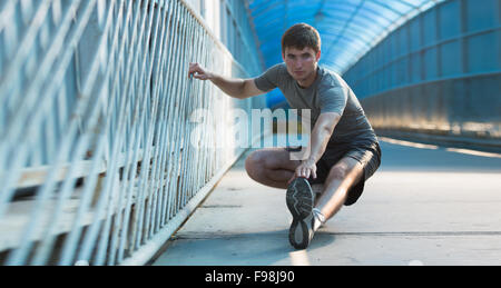 L uomo lo stiramento all'aperto in città Foto Stock