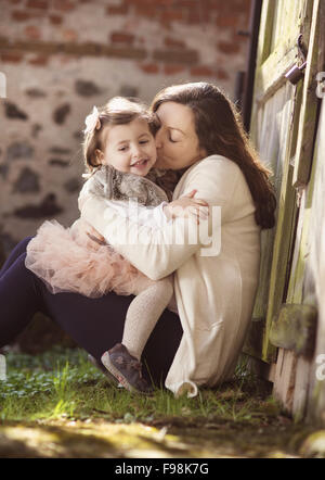 Ritratto di bambina baciando la sua madre in stato di gravidanza Foto Stock