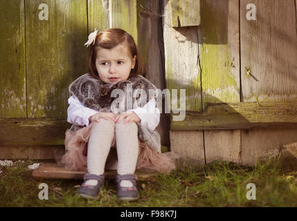 Outdoor ritratto di incantevole piccola ragazza seduta sul vecchio tetto alto Foto Stock