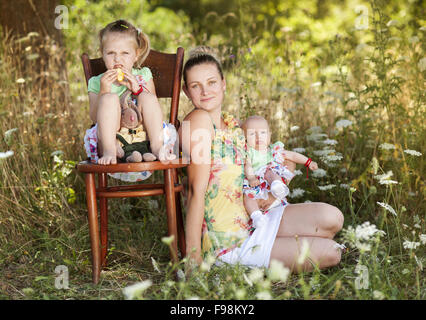 Felice giovane madre di trascorrere del tempo con il suo piccolo figlie nel verde della natura. Foto Stock