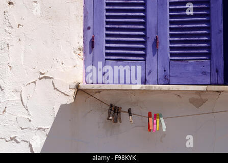 Chiusa la finestra blu scuri e vestiti pin sulla fune Foto Stock