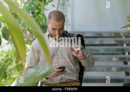 Bello elegante imprenditore parlando al telefono in ufficio Foto Stock