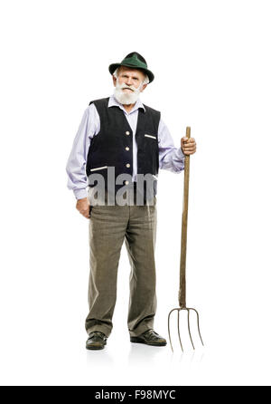 Il vecchio barbuto uomo bavarese in hat holding forcone in mano, isolato su sfondo bianco Foto Stock