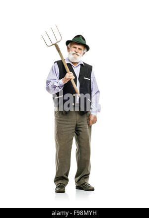 Il vecchio barbuto uomo bavarese in hat holding forcone in mano, isolato su sfondo bianco Foto Stock