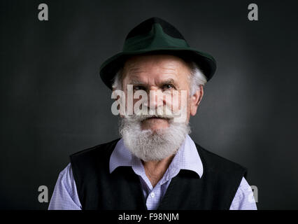 Ritratto di vecchio barbuto uomo bavarese in feltro tradizionale hat, ponendo in studio su sfondo nero Foto Stock