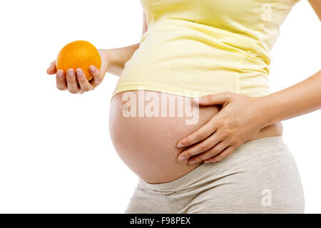 Irriconoscibile donna incinta holding arancione, isolati su sfondo bianco Foto Stock