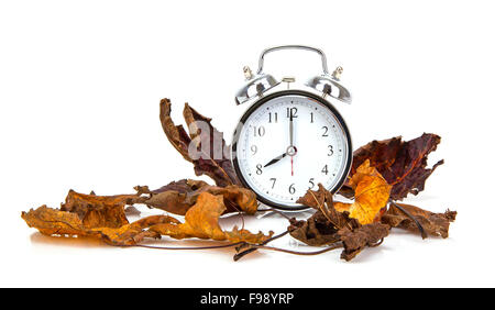 Il vecchio stile orologio sveglia con foglie di autunno su sfondo bianco Foto Stock