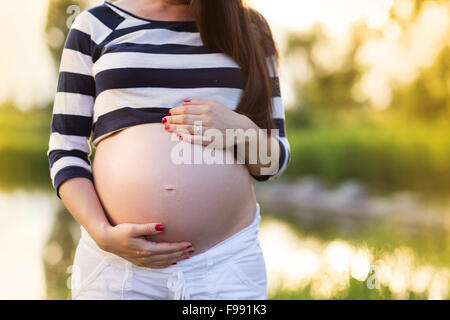 Ritratto all'aperto di un irriconoscibile donna incinta mentre tiene il suo ventre Foto Stock