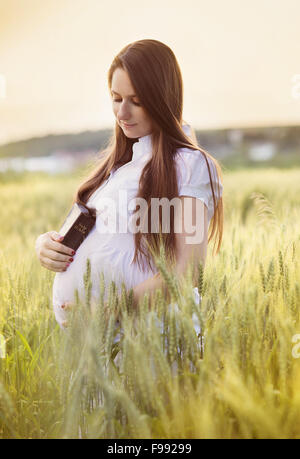 Outdoor Ritratto di giovane donna incinta pregando nel campo Foto Stock