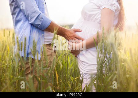 Outdoor Ritratto di giovane coppia incinta nel campo Foto Stock