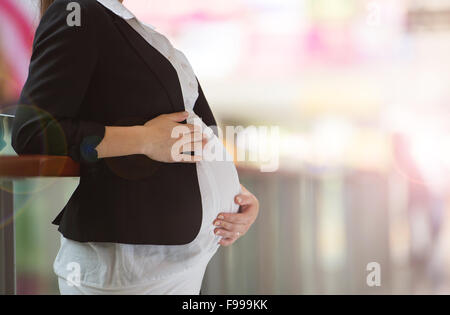 Irriconoscibile donna incinta mentre tiene il suo ventre nel centro commerciale per lo shopping Foto Stock