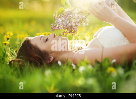 Bella ragazza è rilassarsi sdraiati sull'erba in giardino Foto Stock