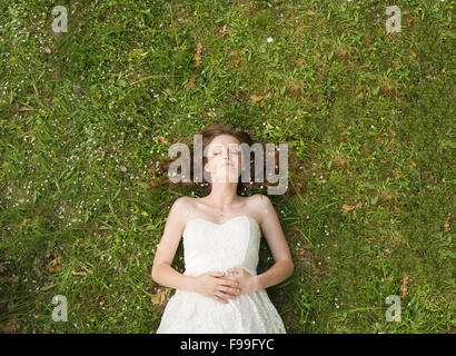 Ragazza giovane sdraiati sull'erba nel parco verde Foto Stock