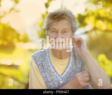 Ritratto di donna senior in grembiule nel giardino soleggiato Foto Stock