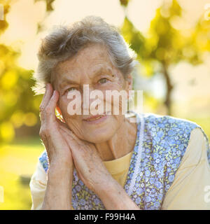 Ritratto di donna senior in grembiule nel giardino soleggiato Foto Stock